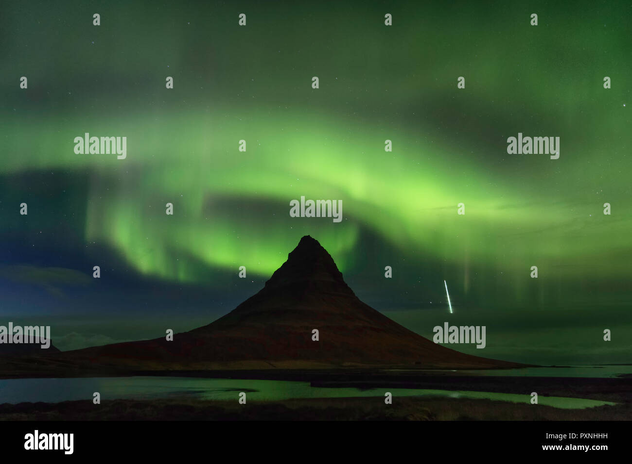 Grundarfjörður, Island - die Aurora borealis Spiralen über der Oberseite der Gipfel des Mount Kirkjufell als Shooting Star Weg durch die Atmosphäre. Stockfoto