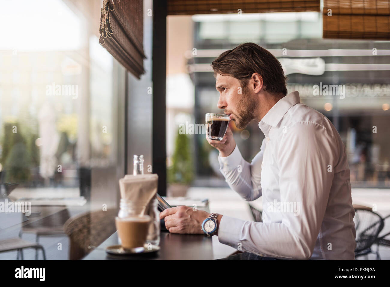 Geschäftsmann mit Tablette in ein Cafe trinken Kaffee aus Glas Stockfoto