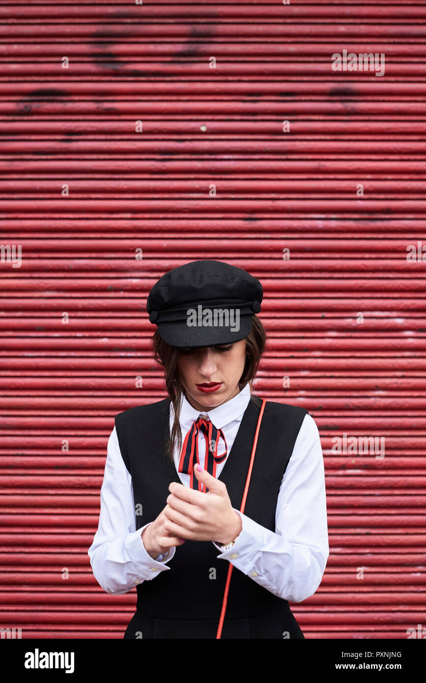 Modische Frau mit roten Lippen tragen schwarze Schirmmütze stand vor der Roten Rollladen Stockfoto