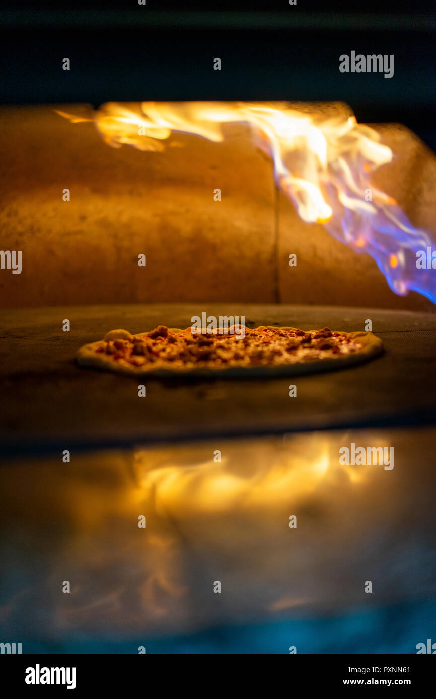 Pizza in Ofen mit brennenden Flamme Stockfoto
