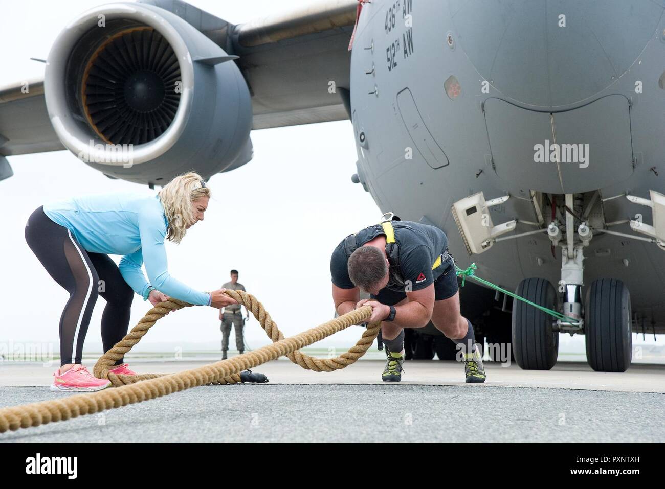 Kate Lord, Ehefrau von Cmdr. Grant Edwards, australische Bundespolizei, Botschaft von Australien, Washington, D.C., und bewegt sich über Seil für Grip am 16. Juni 2017 eingesetzt, auf Dover Air Force Base, Del Edwards, ein australischer strongman Athleten, Ziehen einer C-17 Globemaster III versucht nach 736Th Aircraft Maintenance Squadron Betreuer das Luftfahrzeug für seinen dritten Versuch am Ziehen der Flugzeuge mit einem Gewicht von 418,898 Pfund neu positioniert. Er wird festgelegt, um zu versuchen, das Ziehen einer C-17 während der "Donner über Dover: 2017 Dover AFB Open House", August 26-27. Stockfoto