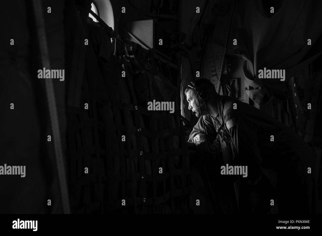 Coast Guard Chief Petty Officer Matthew Youngs, einer Luftfahrt Wartung Techniker mit dem Aviation Logistics Center in Elizabeth City, North Carolina, scannt die Horizont während an Bord einer HC-130 Hercules Flugzeug, 13. Juni 2017. Die Crew mehrere Schulungen tropfen Kenntnisse zu behalten. Stockfoto