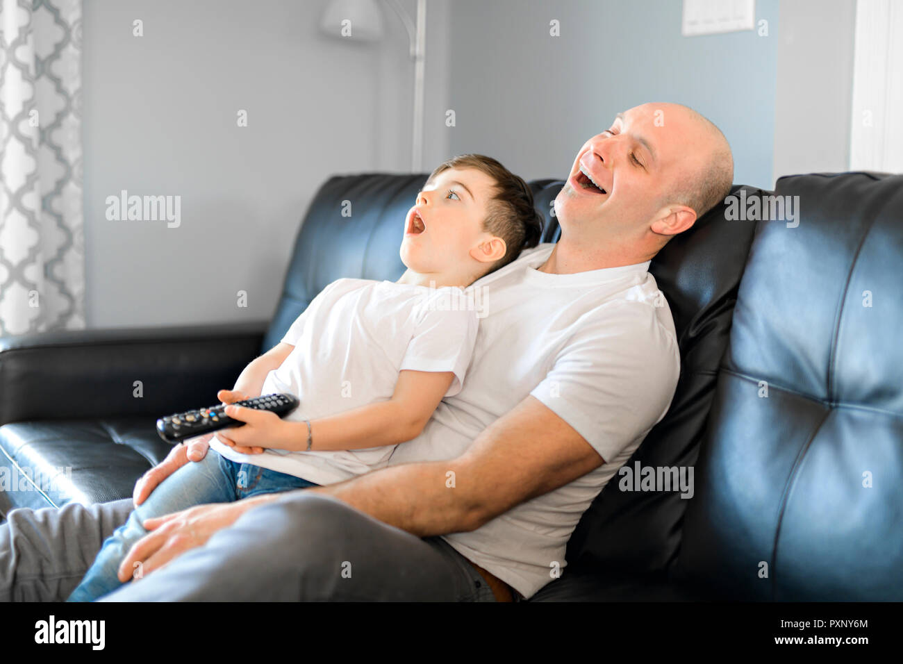 Mann und Junge mit Fernbedienung gähnen Stockfoto