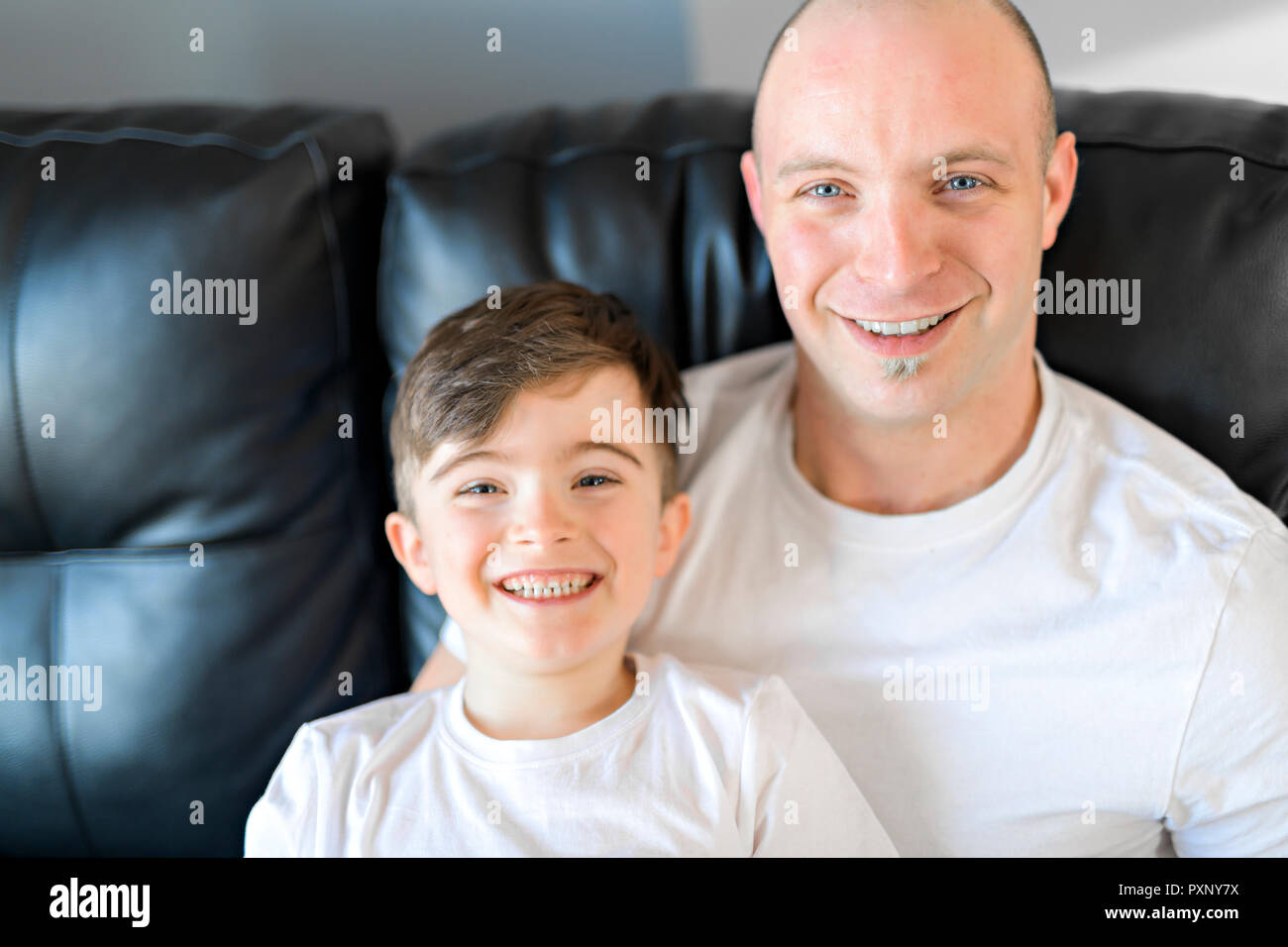 Mann und Junge lächelnd auf dem Sofa Stockfoto
