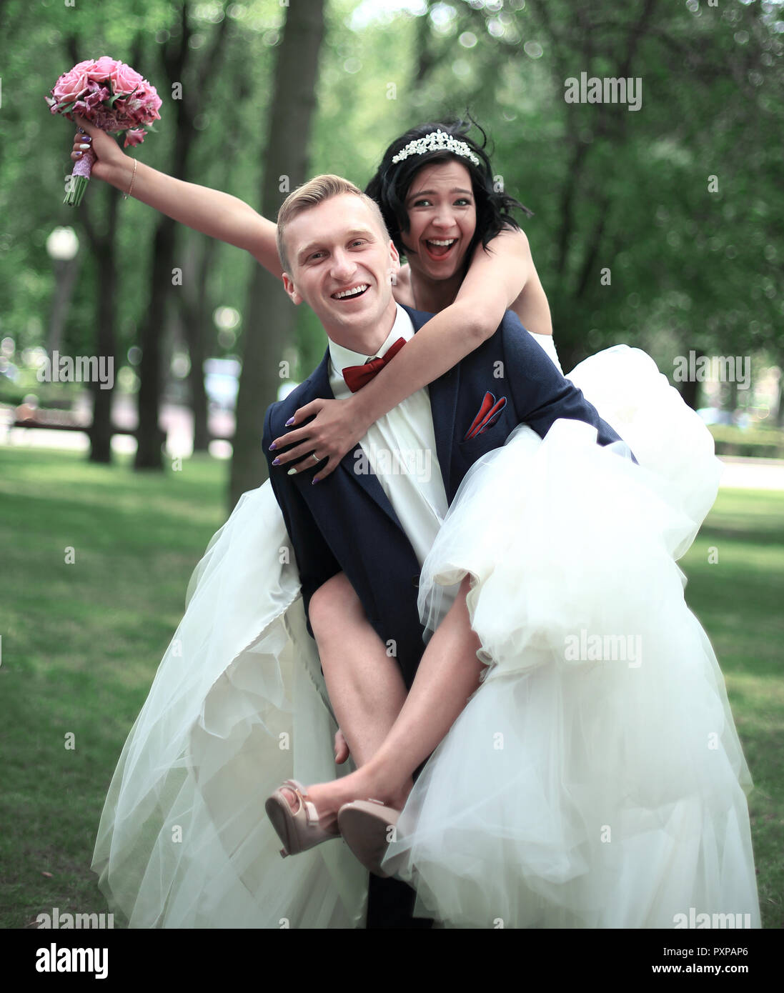Lustig der Bräutigam seine Braut auf der Rückseite im Park Stockfoto