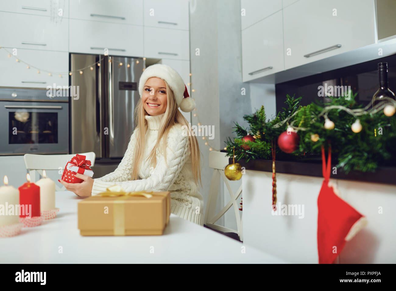 Ein blondes Mädchen in einem Santa Claus Hut mit einem Geschenk in der Hand für C Stockfoto