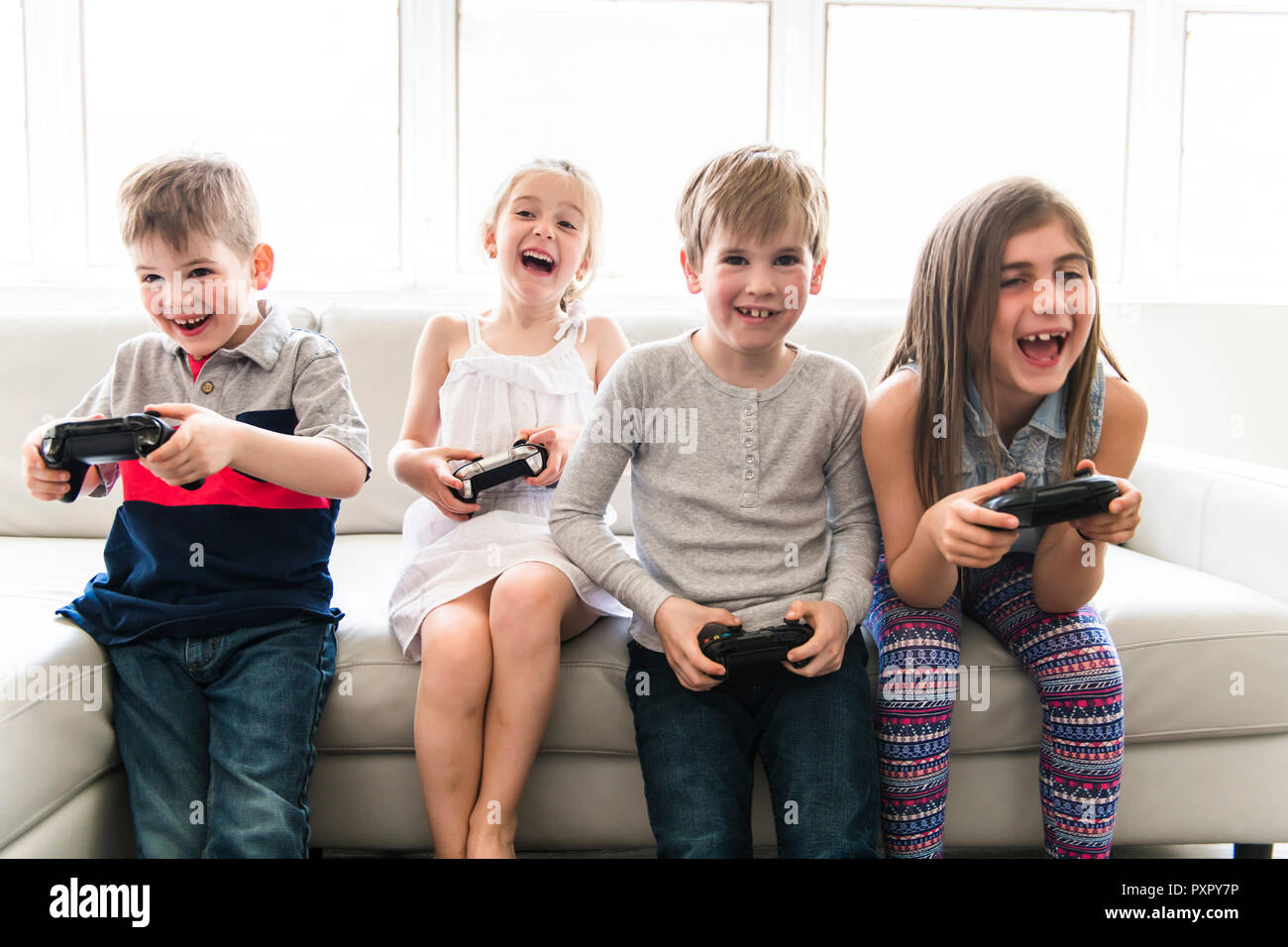 Fröhliche Kinder sitzen zusammen auf dem Sofa zu Hause spielen video game Stockfoto