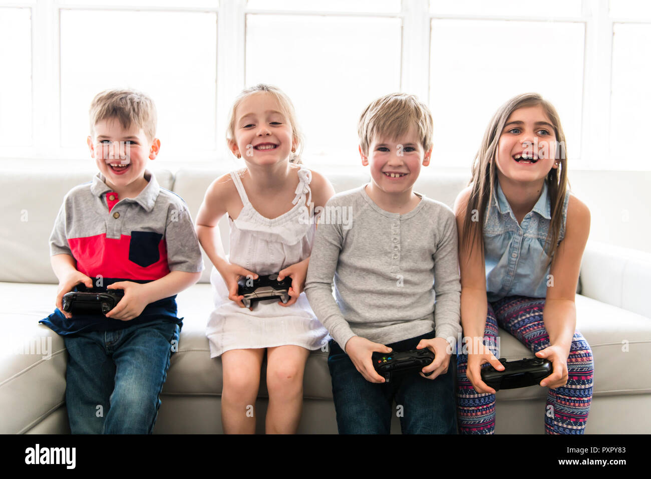 Fröhliche Kinder sitzen zusammen auf dem Sofa zu Hause spielen video game Stockfoto