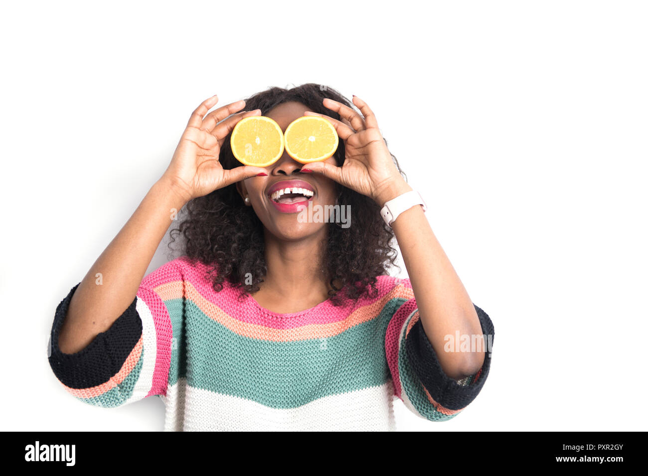 Schwarze Frau Holding orange Frucht in der Nähe des Auges Stockfoto