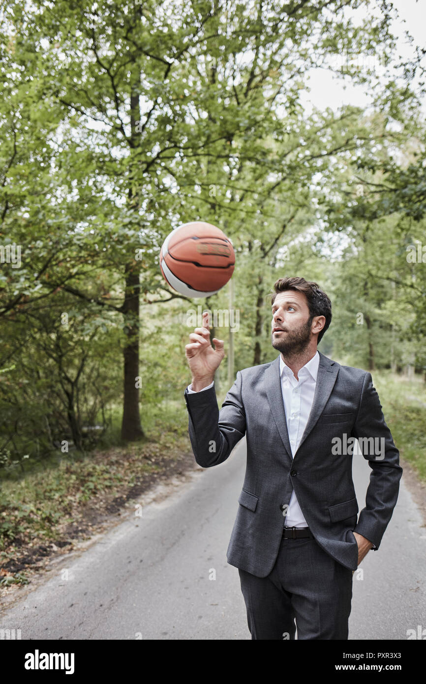 Geschäftsmann balancing Basketball auf ländlichen Straßen Stockfoto