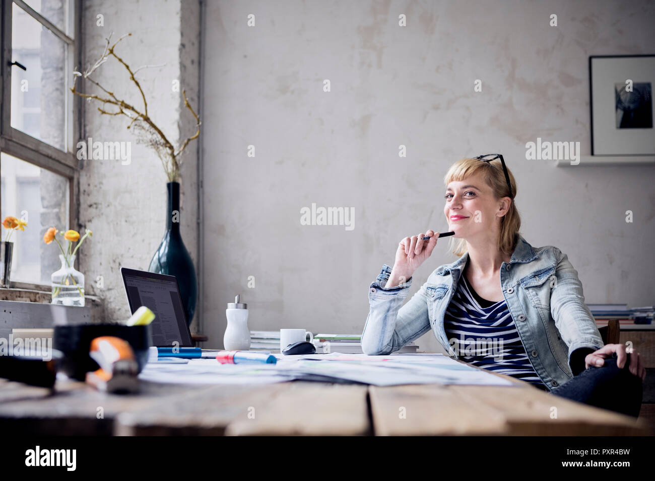 Porträt der lächelnde Frau am Schreibtisch sitzen in einem Loft Stockfoto