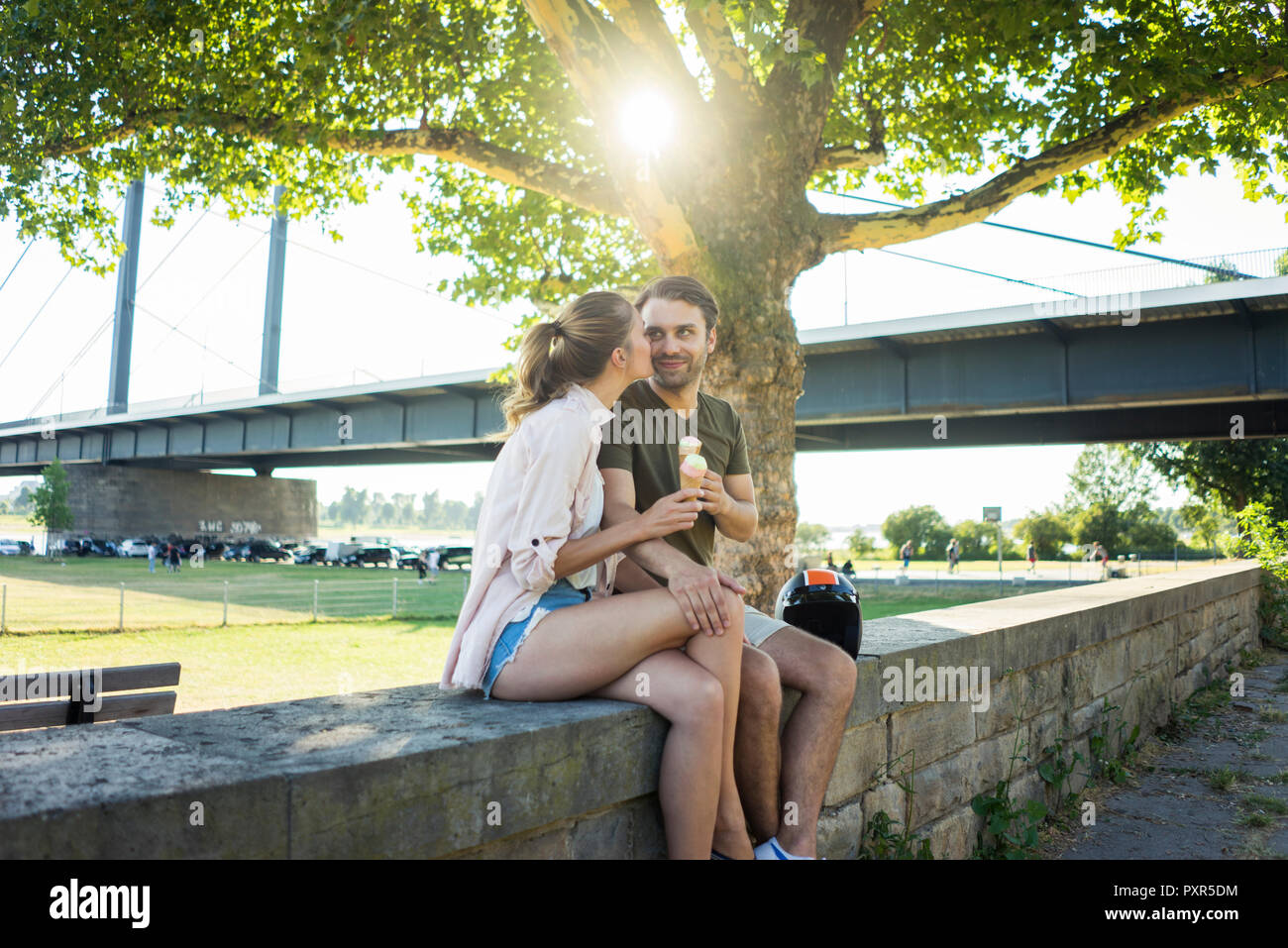 Glückliches Paar sitzen auf einer Mauer im Sommer Eis essen Stockfoto