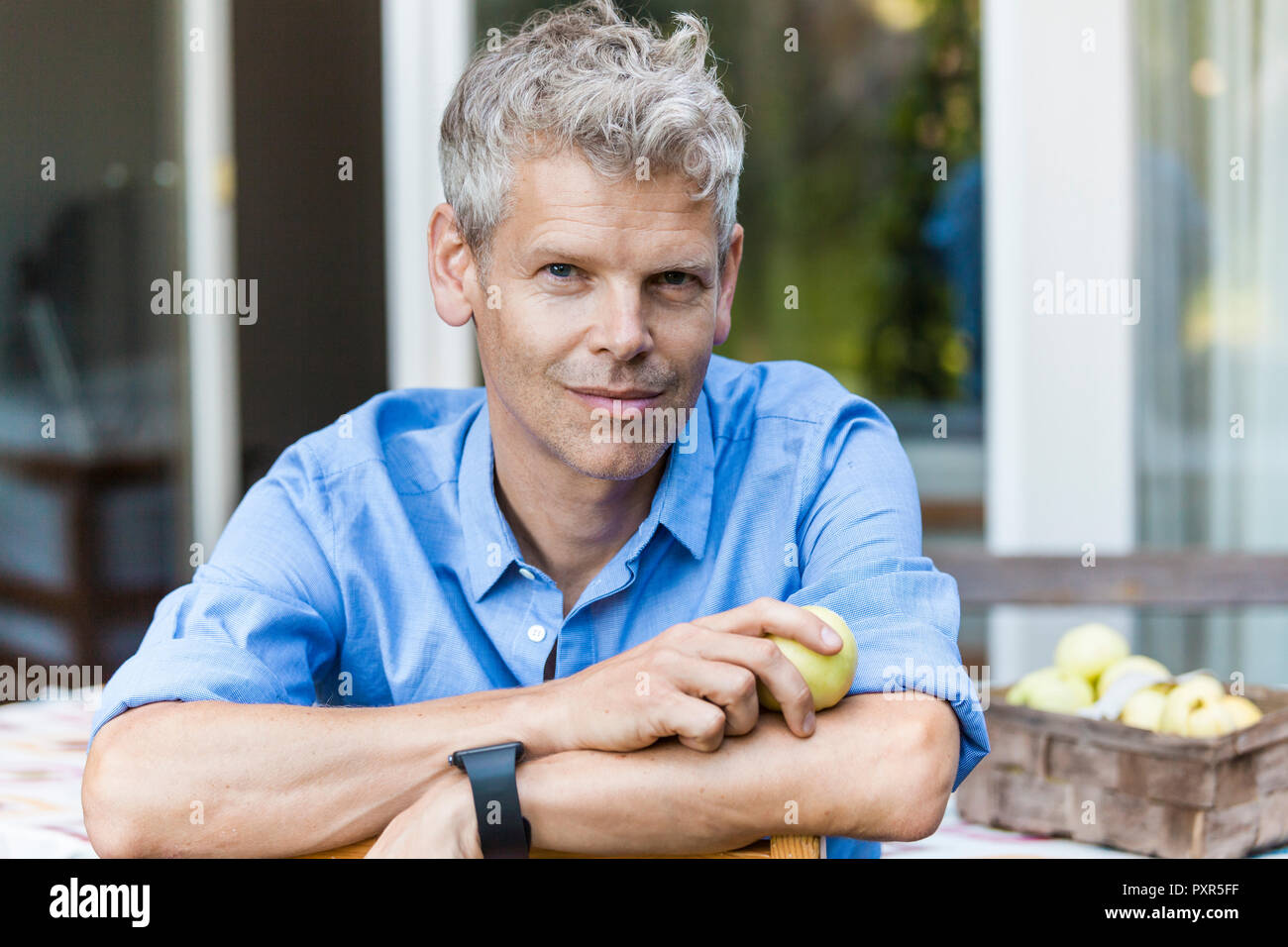 Portrait von lächelnden reifer Mann mit dem grauen Haar sitzen auf der Terrasse Stockfoto