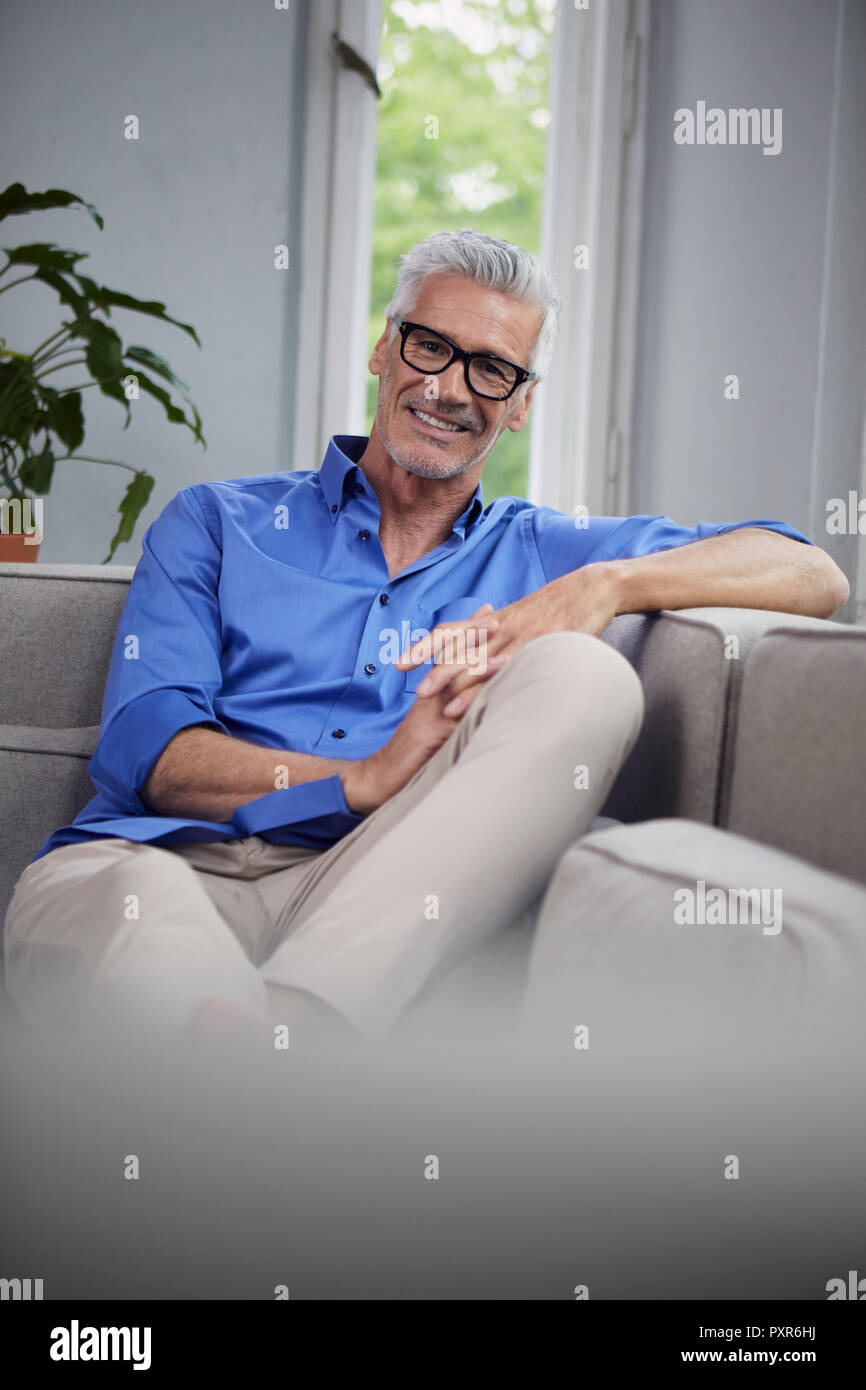 Portrait von lächelnden reifer Mann auf der Couch zu Hause sitzen Stockfoto