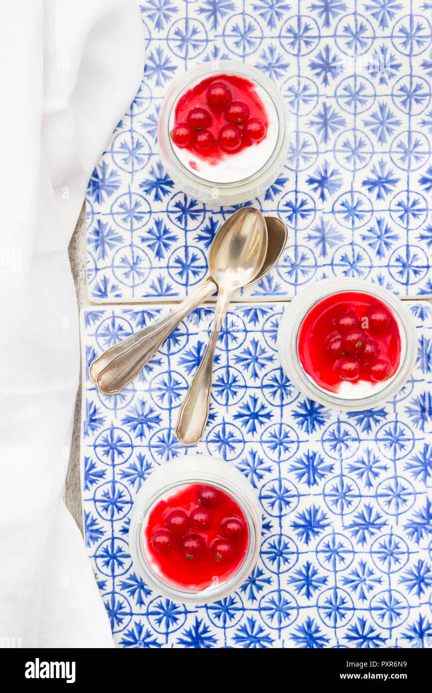 Griechischer Joghurt mit roten Johannisbeeren Sauce auf blau gemusterten Fliesen Stockfoto