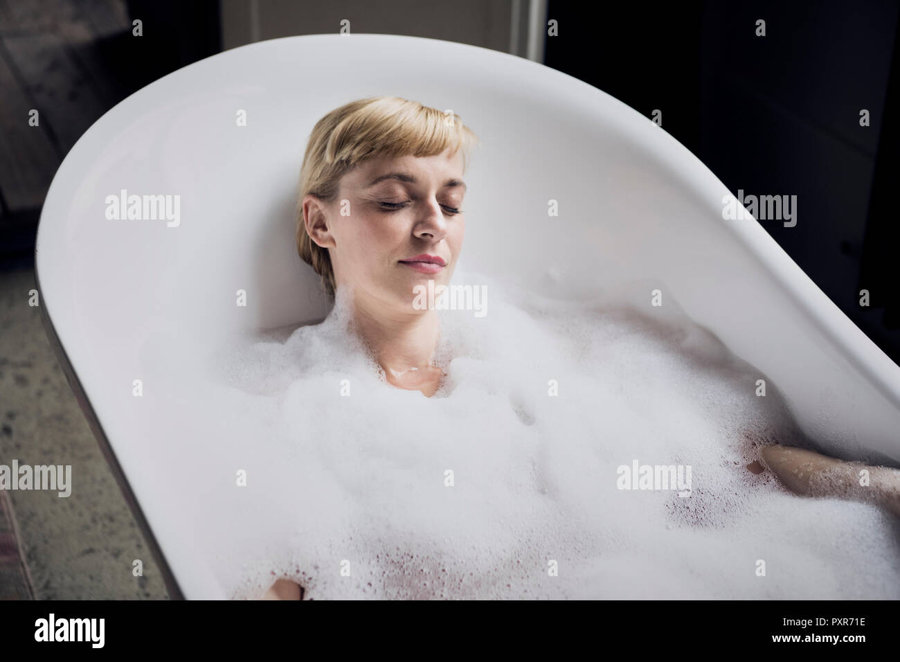 Portrait von Frau mit geschlossenen Augen, Schaumbad in einem Loft Stockfoto