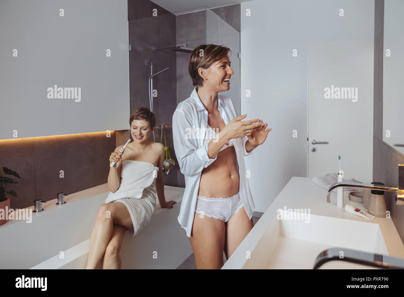 Glückliches lesbisches Paar für Ihr Tag bereit im Badezimmer Stockfoto