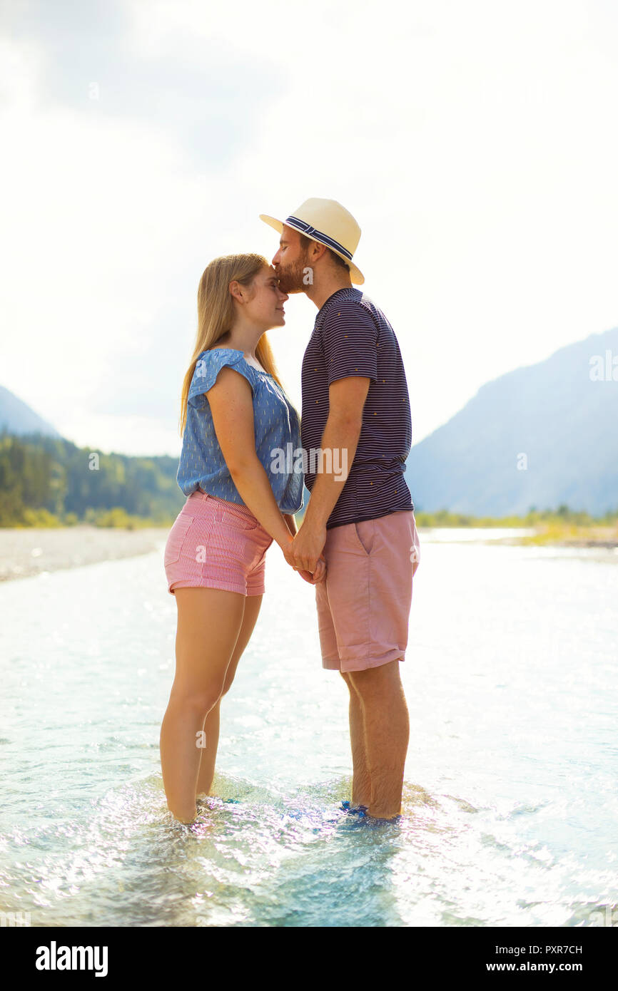 Junges Paar stehend im Wasser, küssen Stockfoto