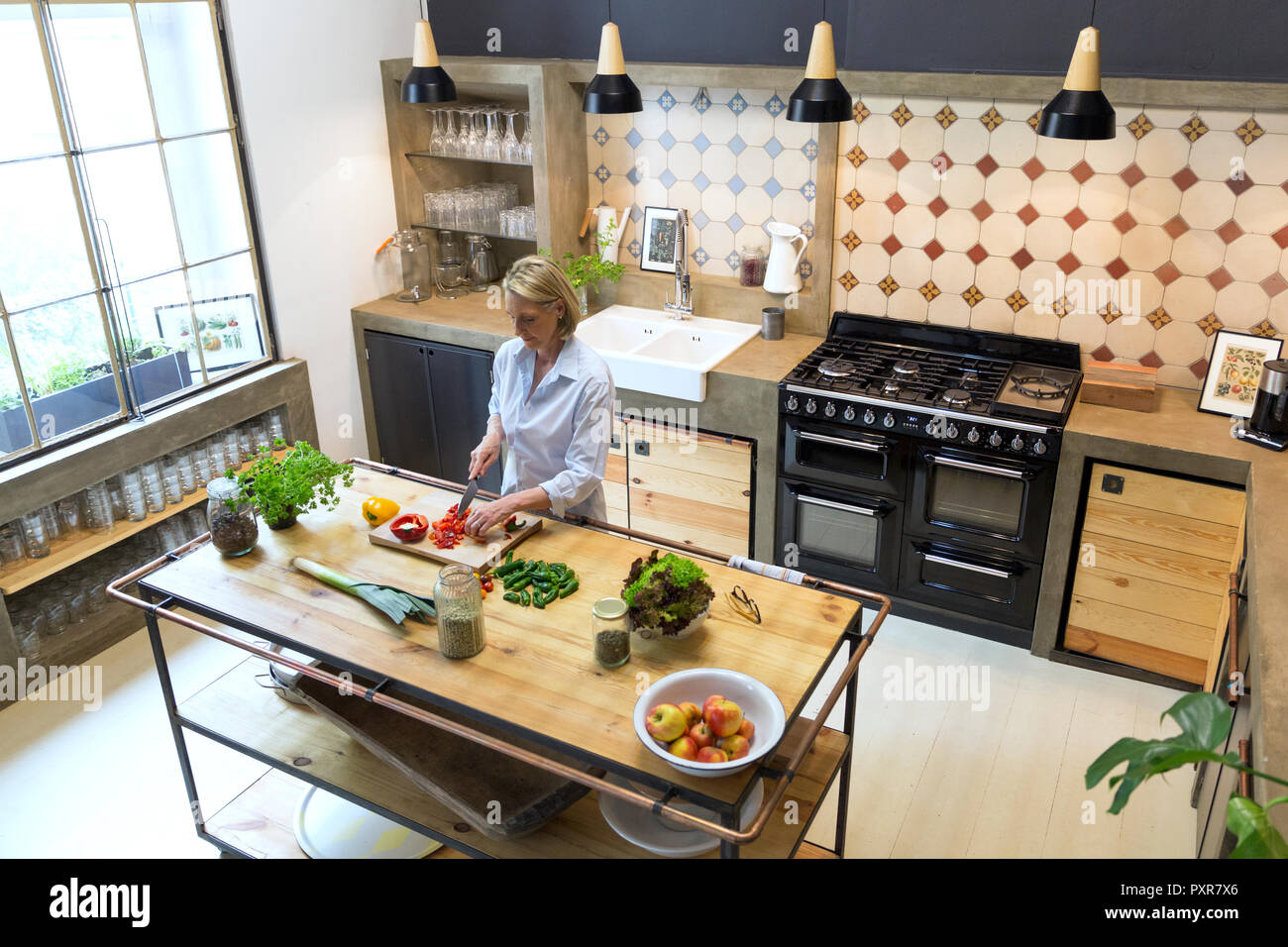 Reife Frau hacken, Paprika in der Küche Stockfoto