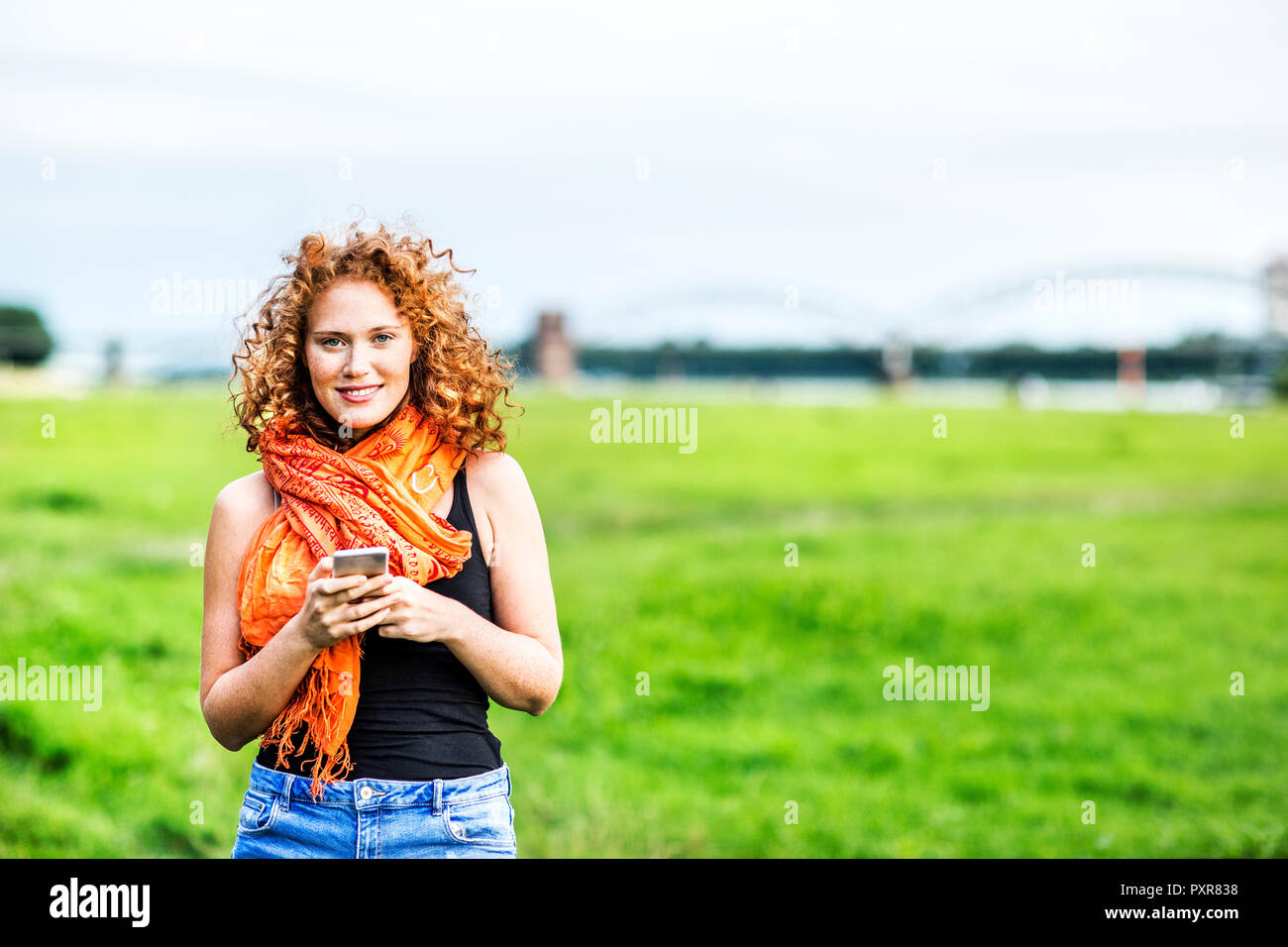 Portrait von lächelnden jungen Frau mit dem lockigen Haar auf einer Wiese Stockfoto