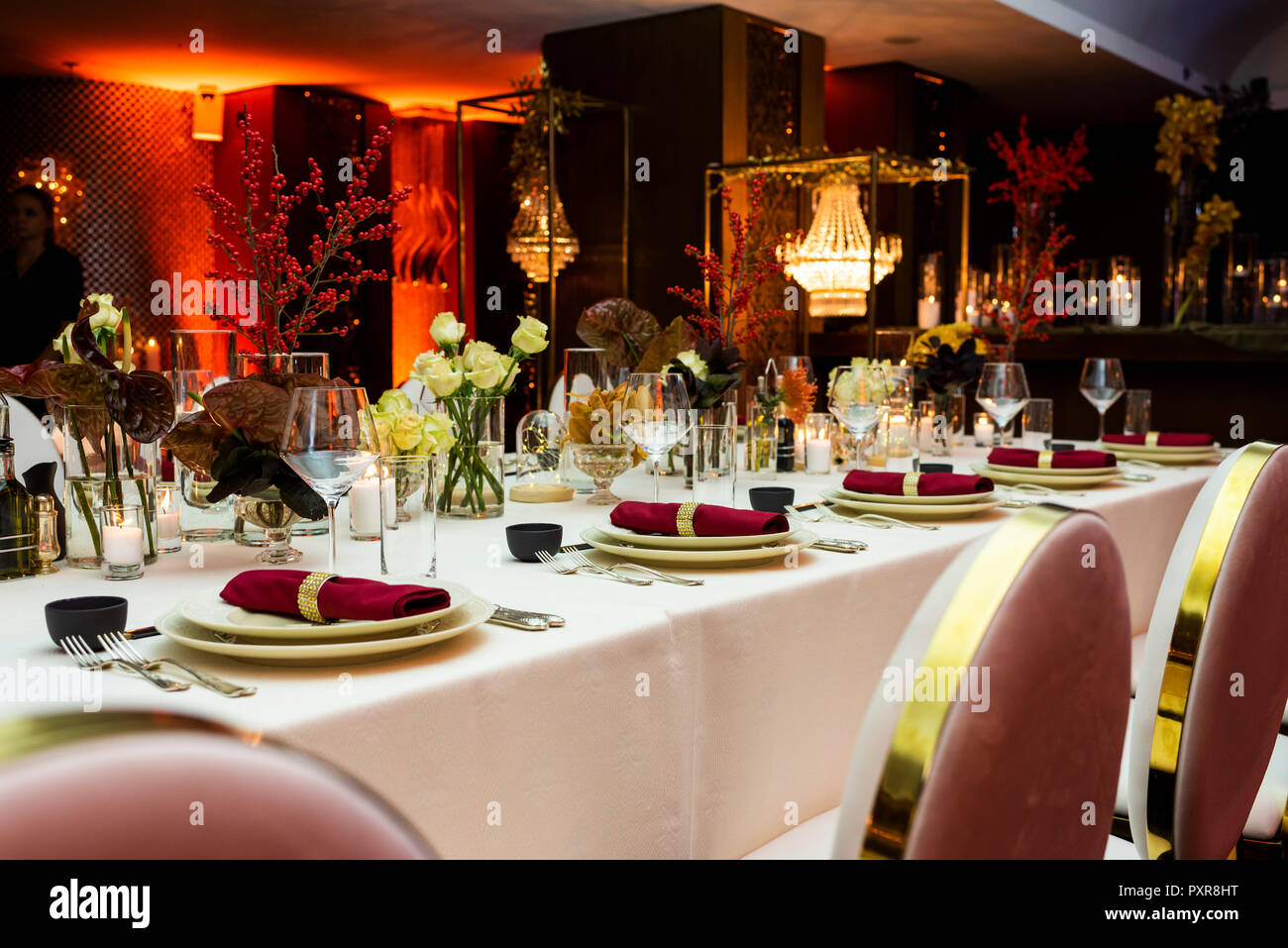 Gedeckter Tisch für eine grosse Feier am Abend in einem Restaurant mit Blumen und Kerzen Stockfoto