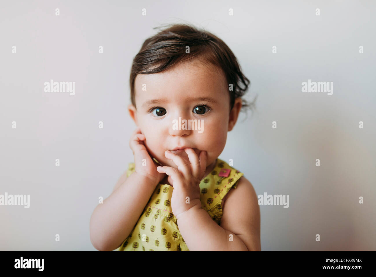 Portrait von Baby Mädchen mit Hand auf Mund auf weißem Hintergrund Stockfoto