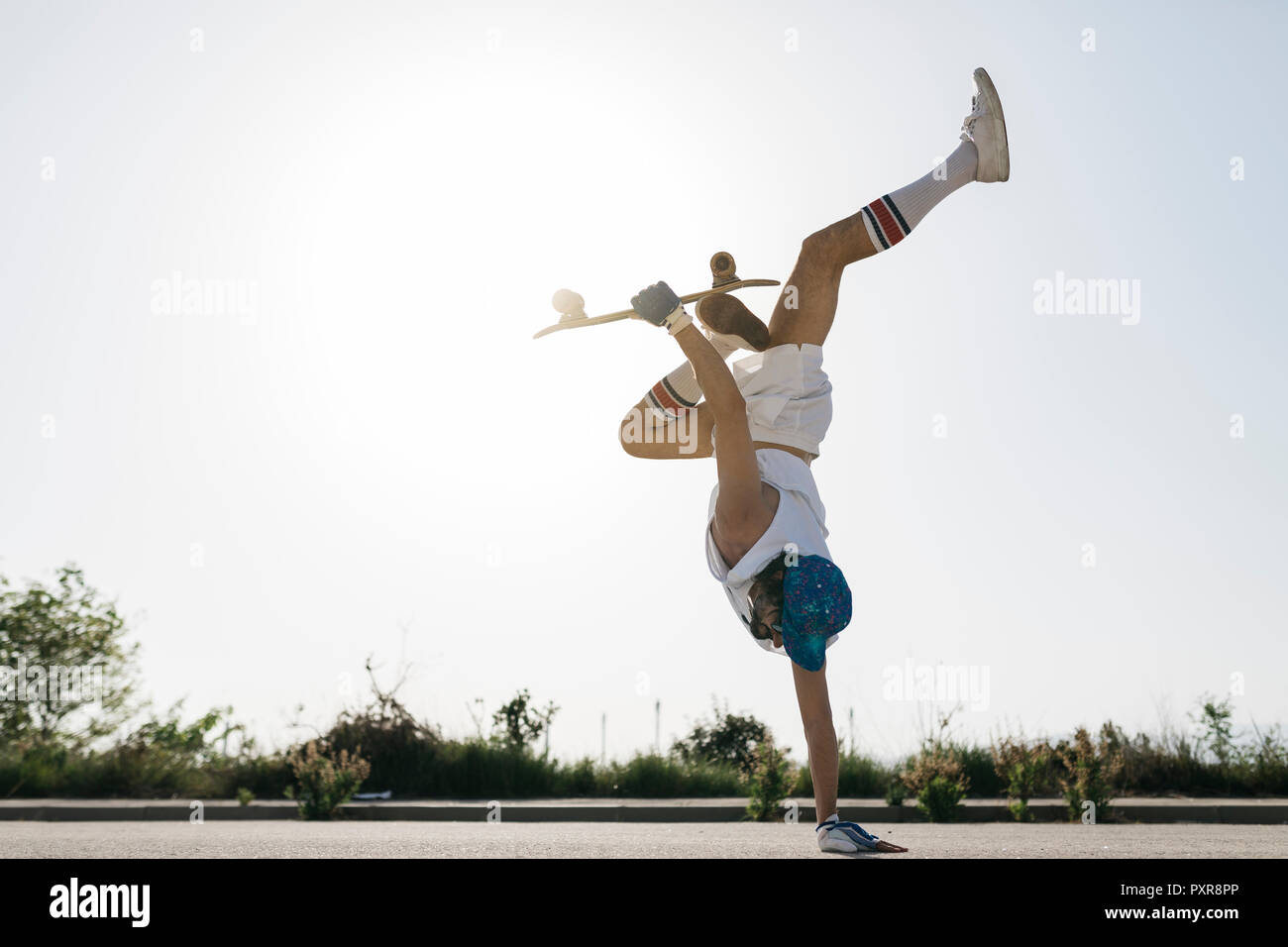 Seitenansicht des sportlichen Mann dabei spannende Trick mit Skateboard spiegeln auf der einen Seite auf der Straße Stockfoto