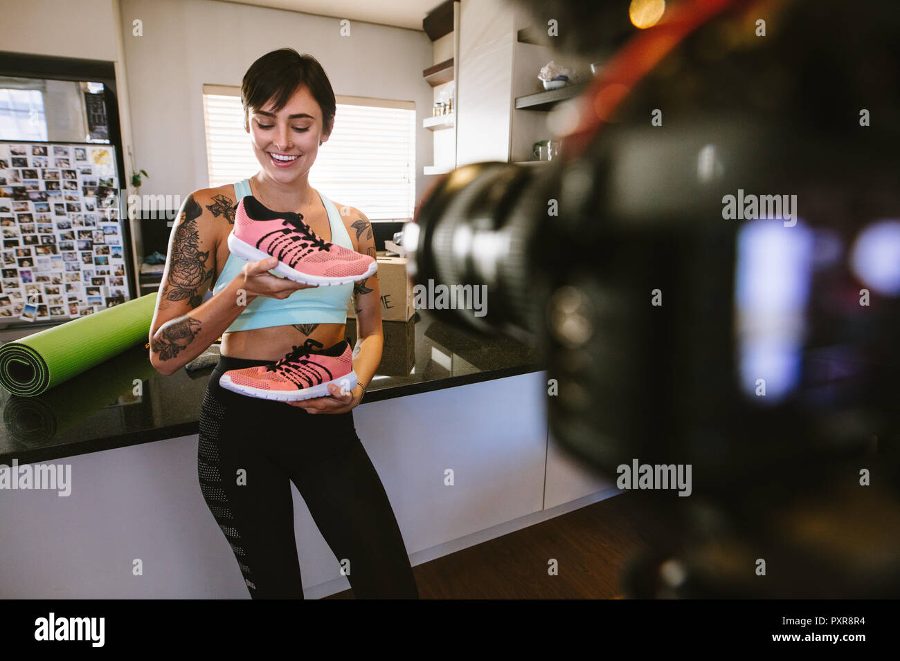 Lächelnd weibliche vlogger Holding Sport Schuhe in den Händen, die Aufnahme neuer Sportswear video für Vlog auf Kamera. Frau social media Einflussnehmer erklärt die b Stockfoto