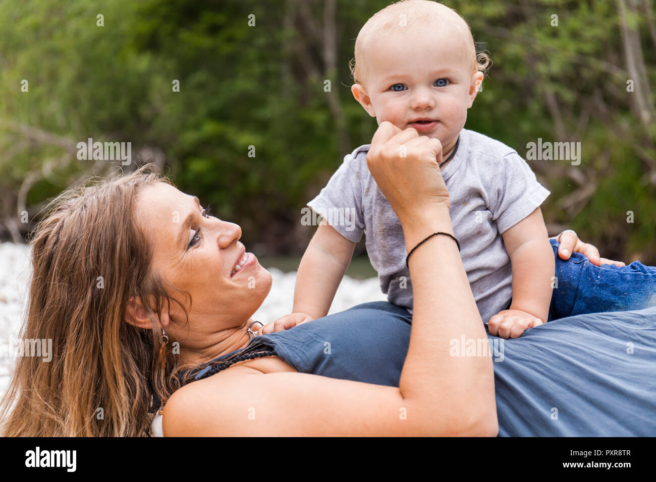 Glückliche Mutter spielt mit baby boy draußen in der Natur Stockfoto