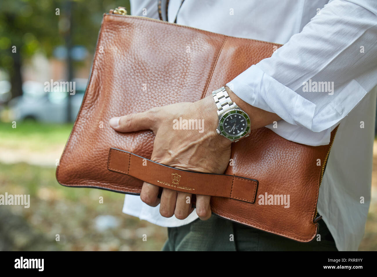 Mailand, Italien - 22. SEPTEMBER 2018: Mann mit grünen Rolex Submariner Watch und braunem Leder Tasche, bevor Simonetta Ravizza fashion show, Mailand Fashion Wir Stockfoto Mailand, Italien - 22. SEPTEMBER 2018: Mann mit grünen Rolex Submariner Watch und braunem Leder Tasche, bevor Simonetta Ravizza fashion show, Mailand Fashion Wir Stockfoto