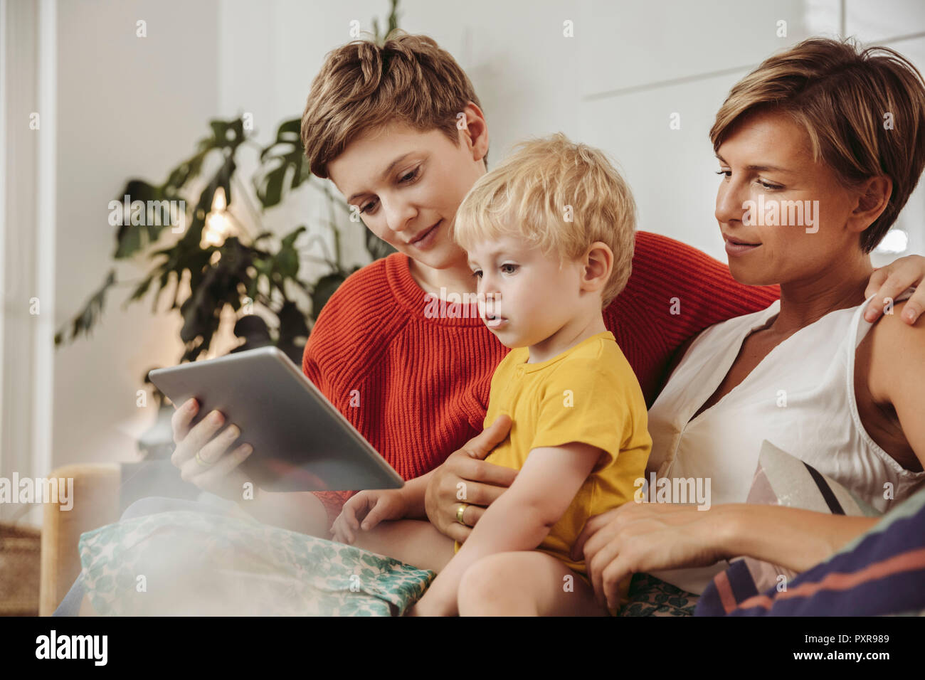 Zwei Mütter mit Blick auf einen Tablet-PC mit Ihrem Kind zu Hause Stockfoto