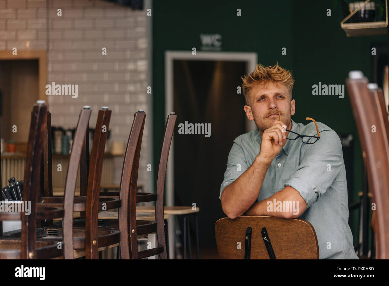 Junge Unternehmer in seinem Café sitzen, denken Stockfoto