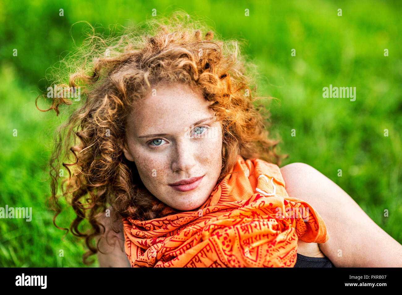 Portrait von Sommersprossige junge Frau mit dem lockigen Haar zu tragen rot orange Schal Stockfoto