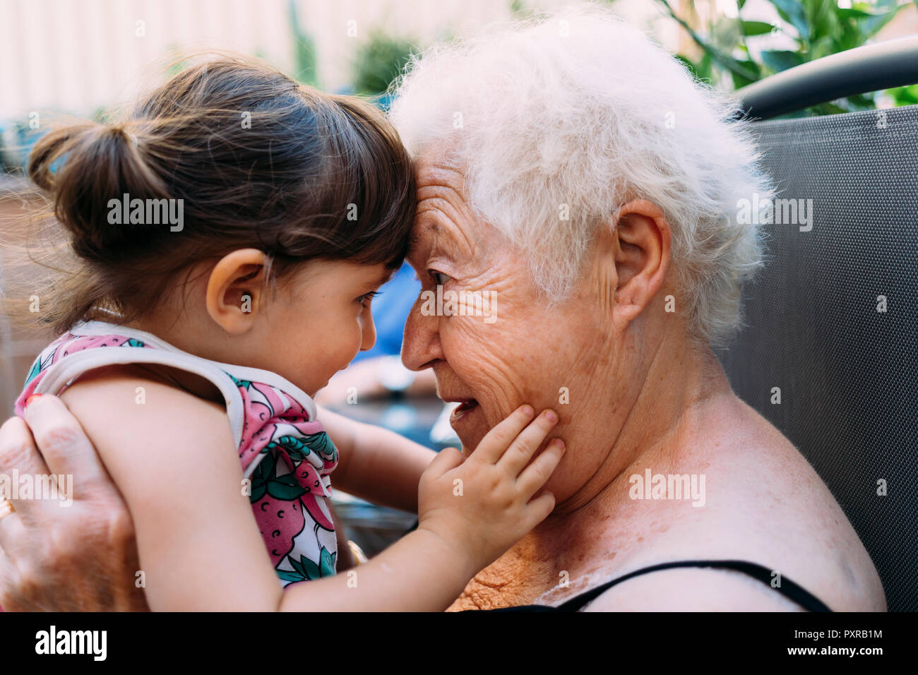 Großmutter mit ihrer Enkelin auf der Terrasse zu Gesicht Stockfoto