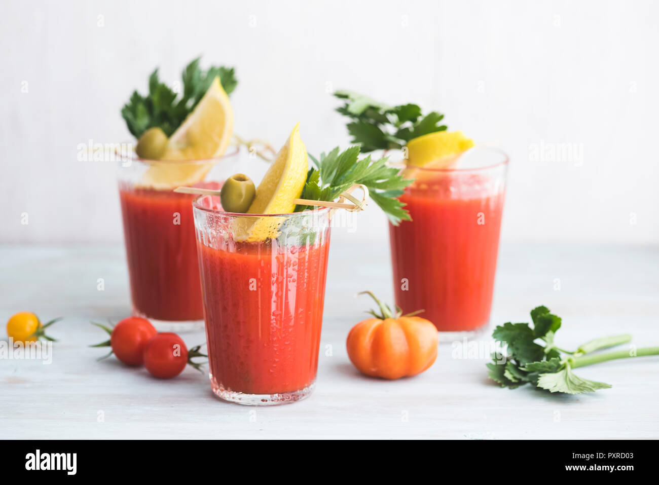 Gläser frisch würzig Tomatensaft mit cellery garniert mit Zitronenscheibe, grünen Oliven und Petersilie Stockfoto