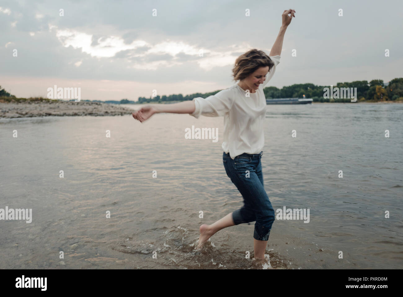 Lachende Frau am Flußufer läuft Stockfoto