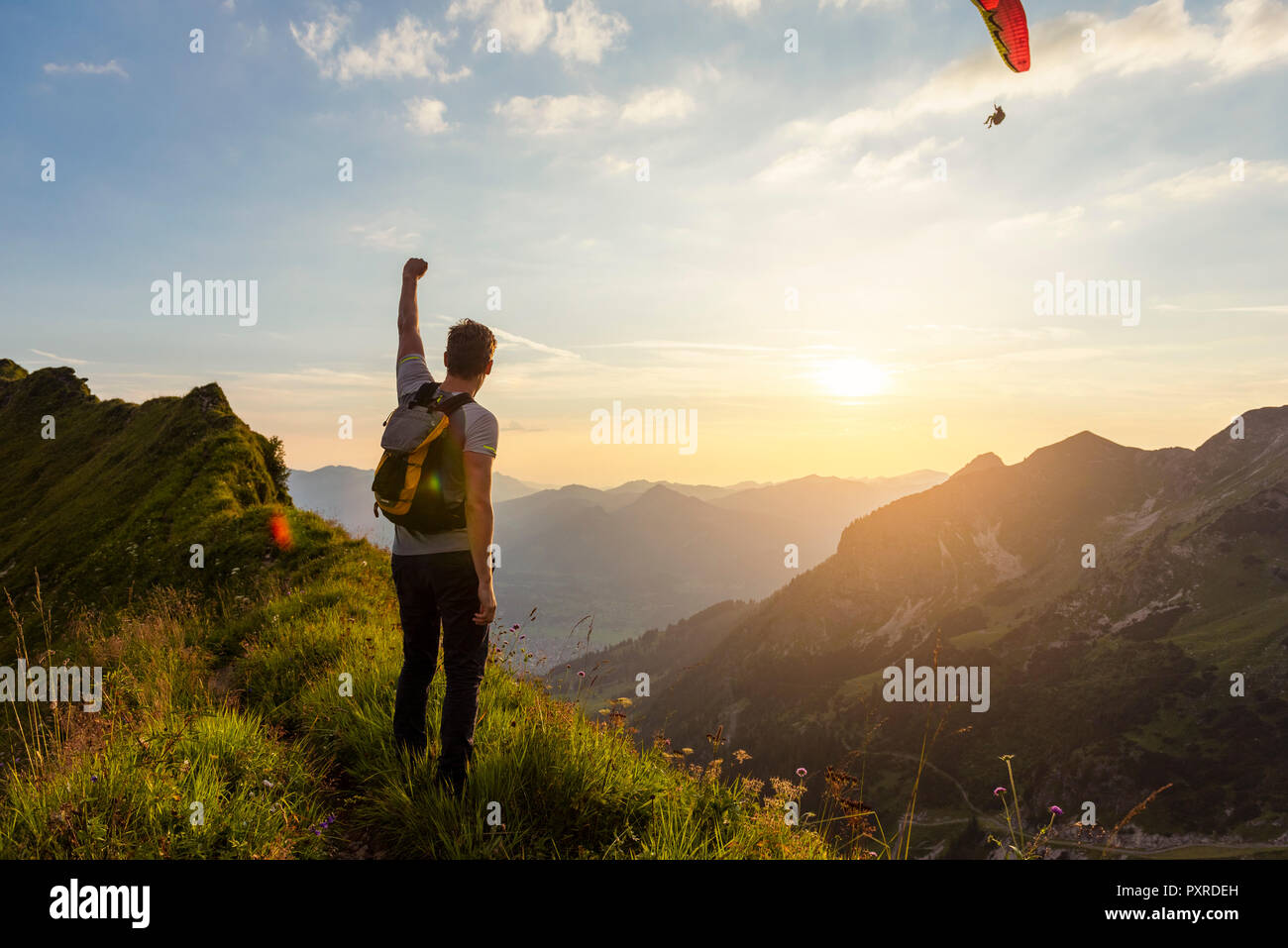 Deutschland, Bayern, Oberstdorf, Mann auf eine Wanderung in die Berge bei Sonnenuntergang mit Gleitschirm im Hintergrund Stockfoto