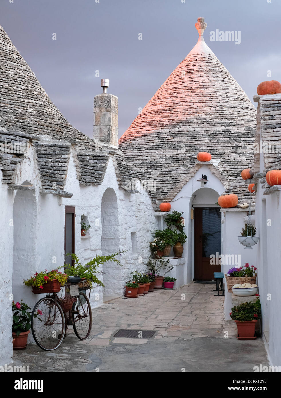 Trulli auf der Straße in Alberobello, Apulien. Kürbisse haben auf der Traufe platziert wurde Halloween zu feiern. Bei Sonnenaufgang fotografiert. Stockfoto