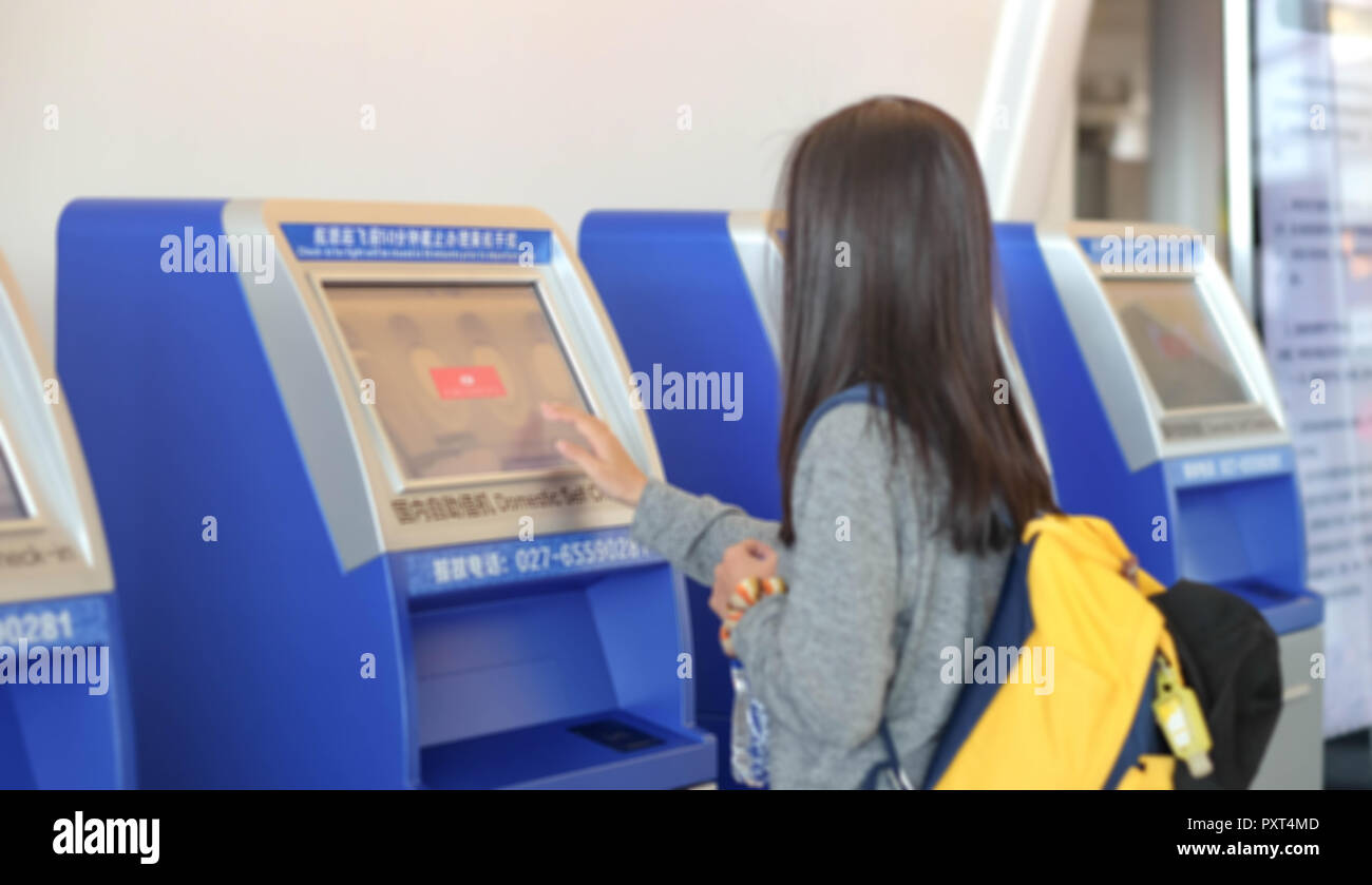 China Wuhan Tianhe - September 10, 2018: Die junge Frau mit dem Check-in-Automaten am Flughafen erhalten der Bordkarte. Es ist blur Bild. Stockfoto