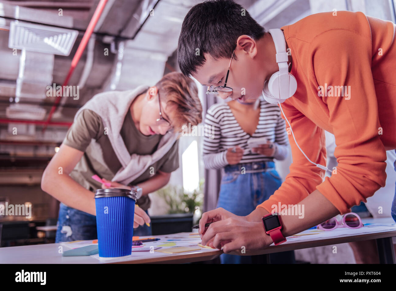 Aufmerksame internationale Schüler seine Freunde helfen bei der Aufgabe Stockfoto