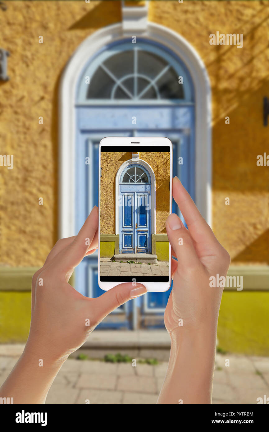 Ein Tourist ist ein Foto des alten schönen hölzernen Tür in der Altstadt von Tallinn, und auf einem Mobiltelefon Stockfoto