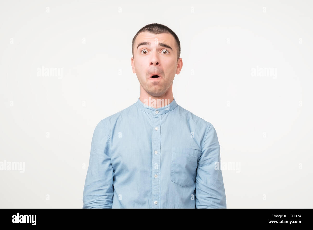 Portrait von ängstlichen jungen Mann im blauen Hemd halten Mund weit offen, Stress Stockfoto