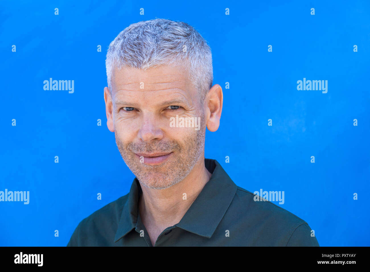 Porträt eines lächelnden reifer Mann an der blauen Wand Stockfoto