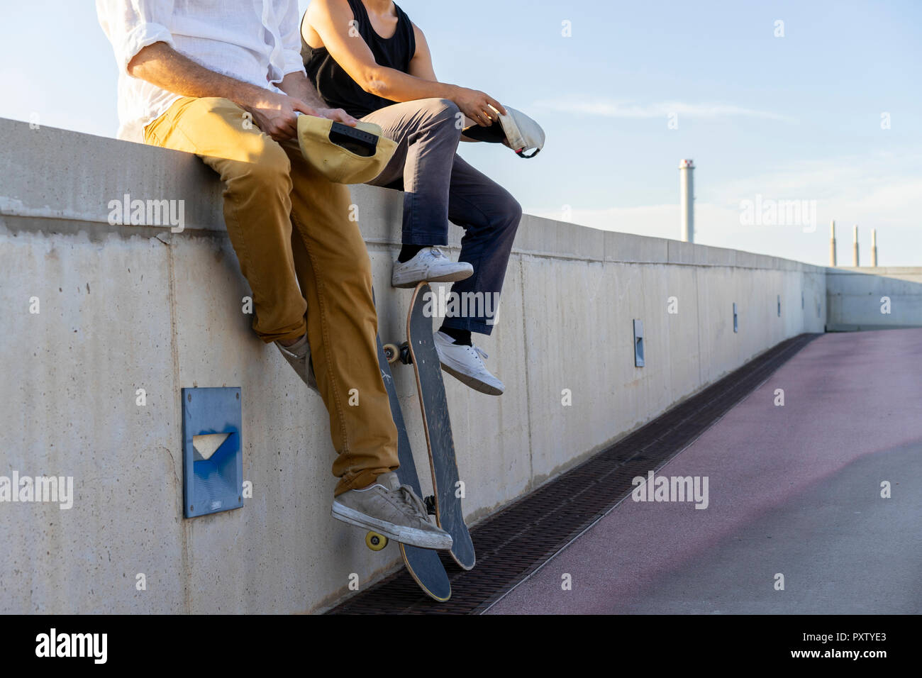 Close-up von zwei jungen Männern mit skateboards sitzen auf einer Mauer Stockfoto