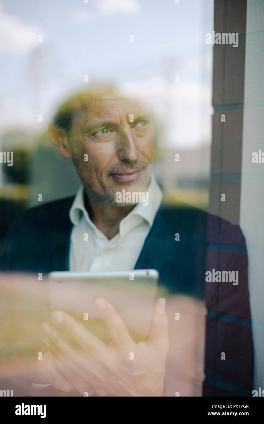 Portrait eines reifen Geschäftsmann stand am Fenster, mit digitalen Tablet Stockfoto
