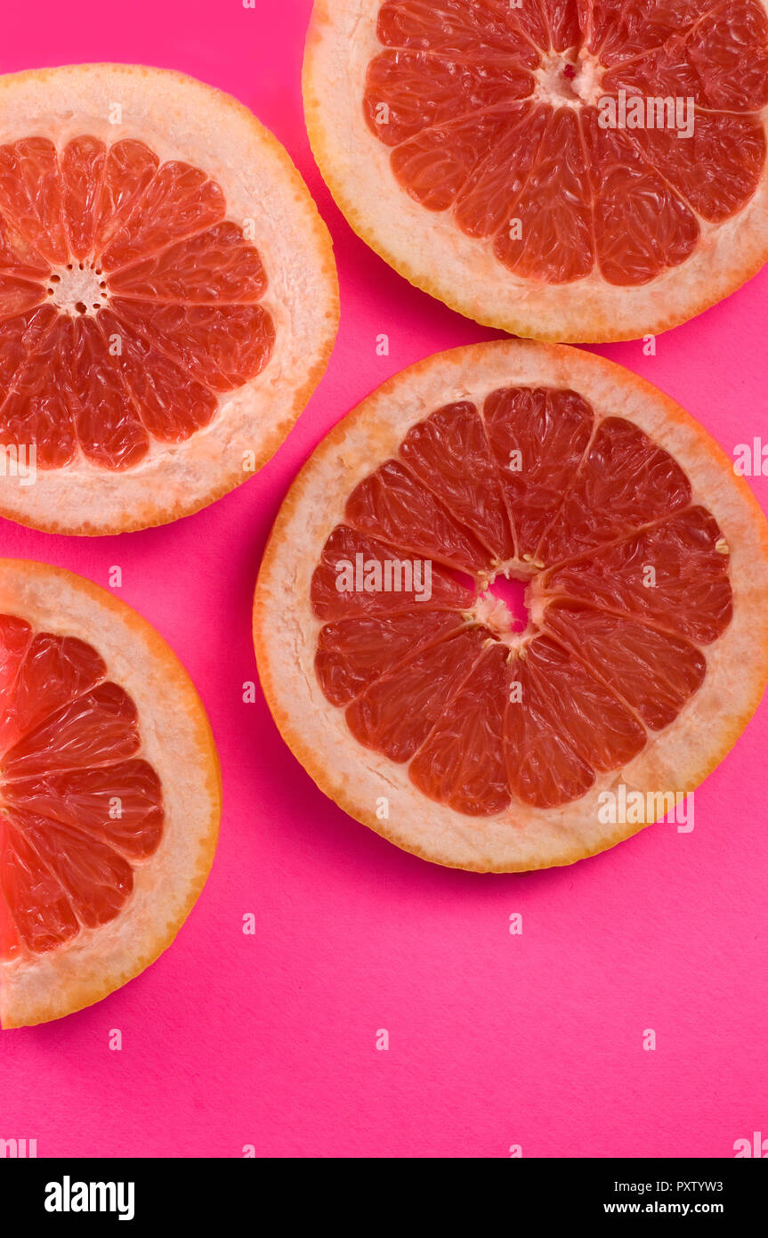Segmente von Pampelmusen und Grapefruits auf rosa Hintergrund Bild vertikal Stockfoto