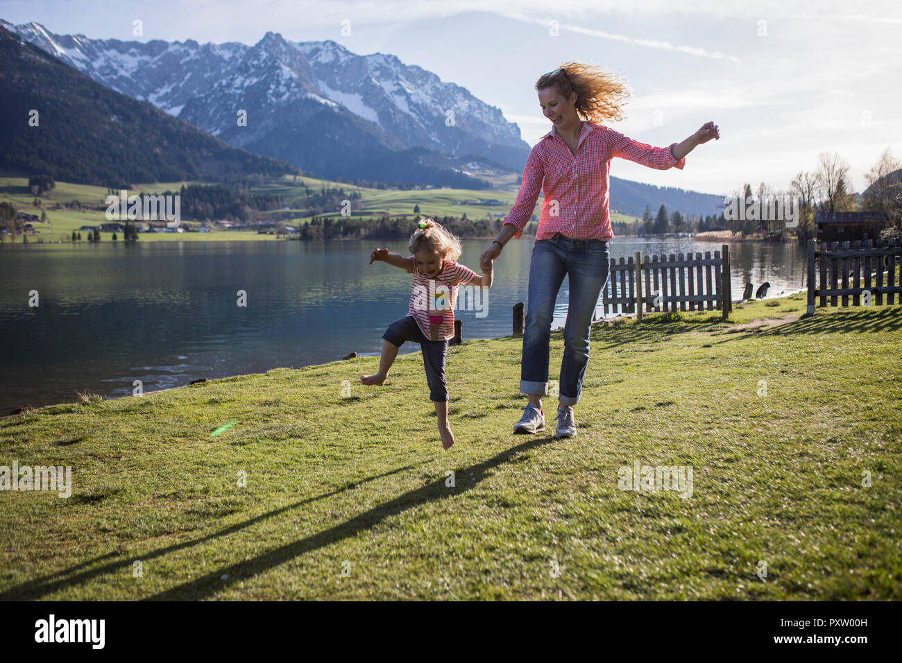 Österreich, Tirol, Walchsee, sorglosen Mutter und Tochter jumping am See Stockfoto