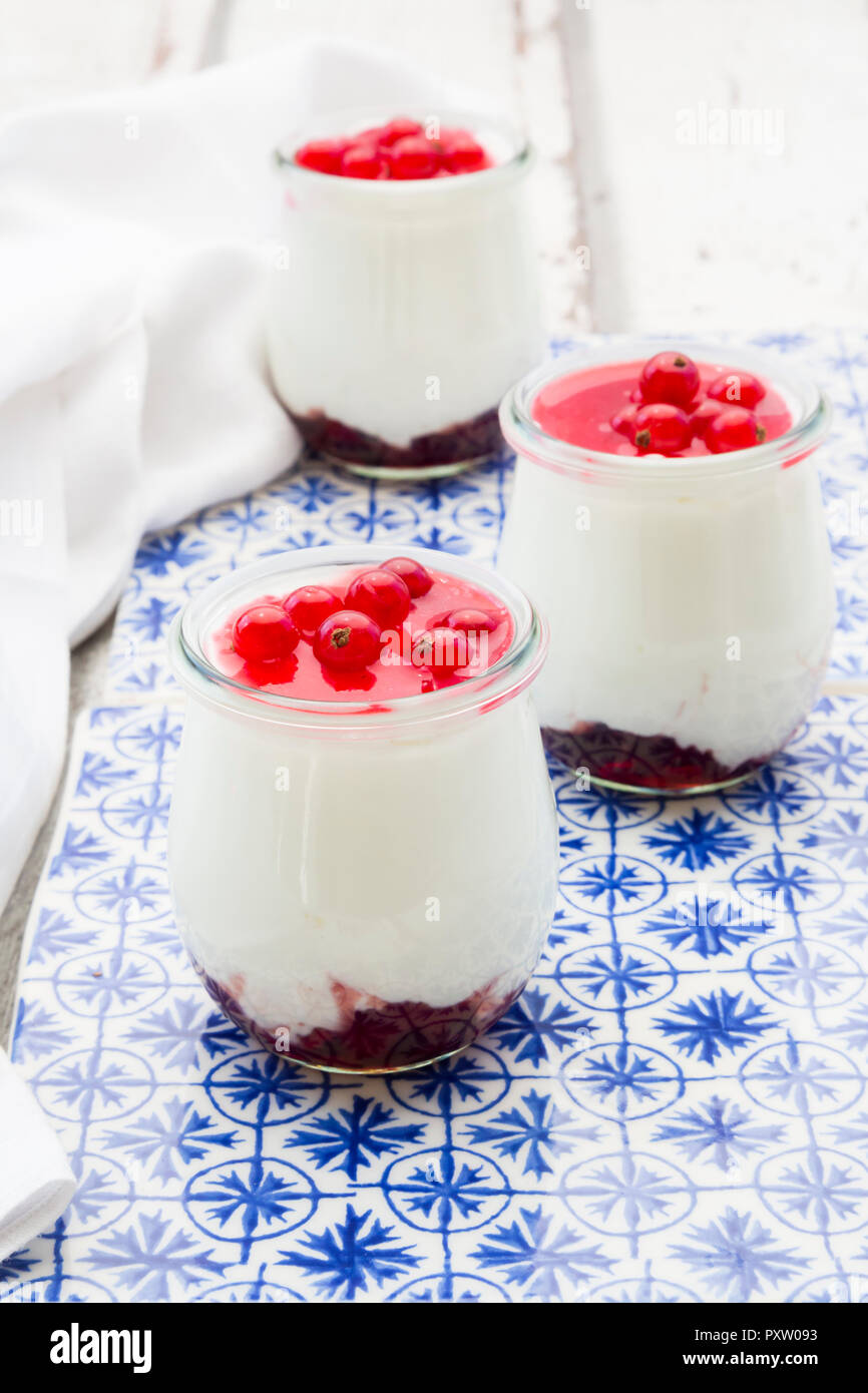 Griechischer Joghurt mit roten Johannisbeeren Sauce auf blau gemusterten Fliesen Stockfoto