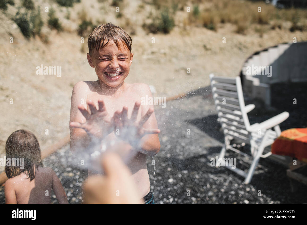 Portrait von lachende Junge im Garten spritzte Stockfoto