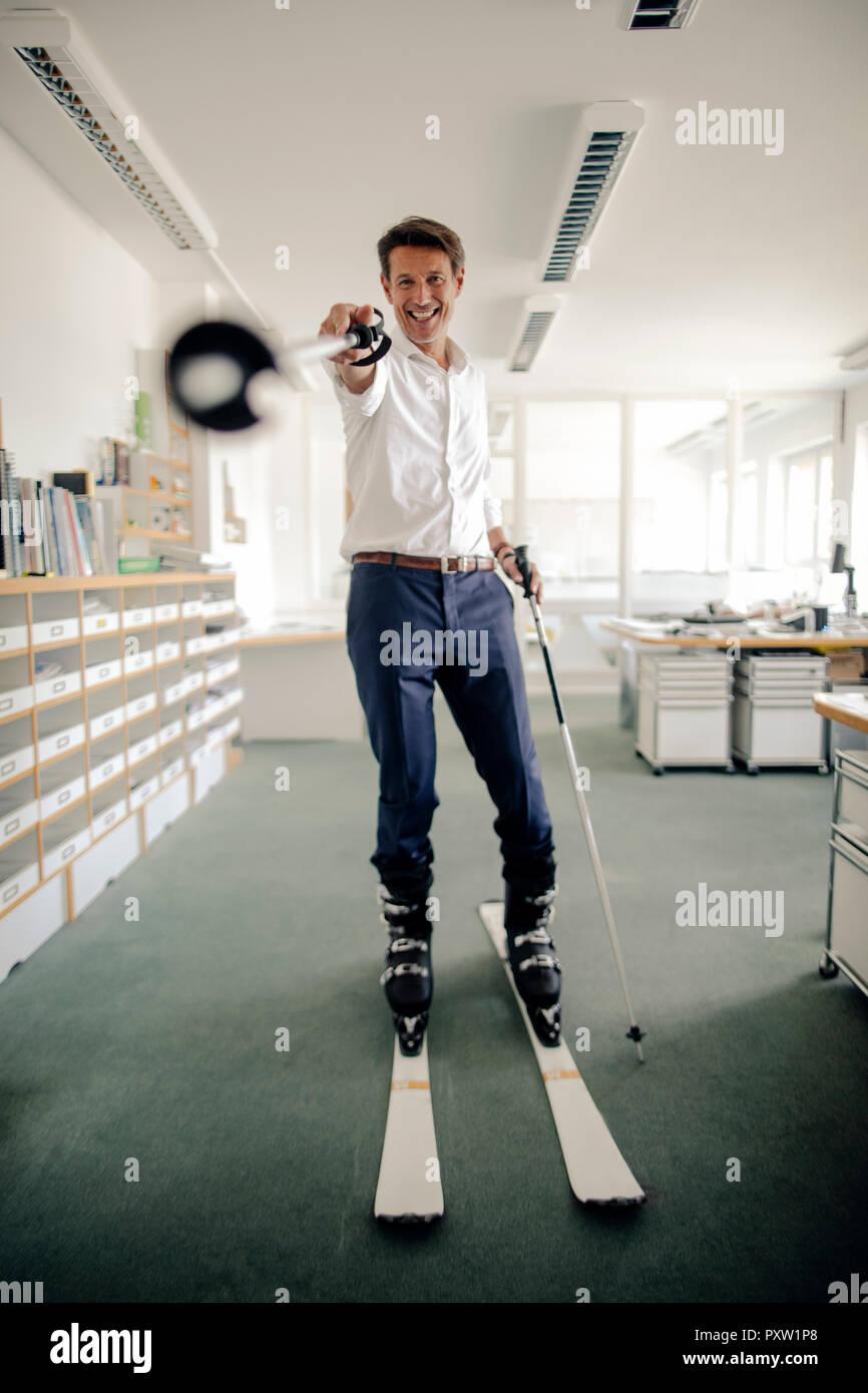 Geschäftsmann Skifahren in Büro und zeigt mit Ski Pole Stockfoto